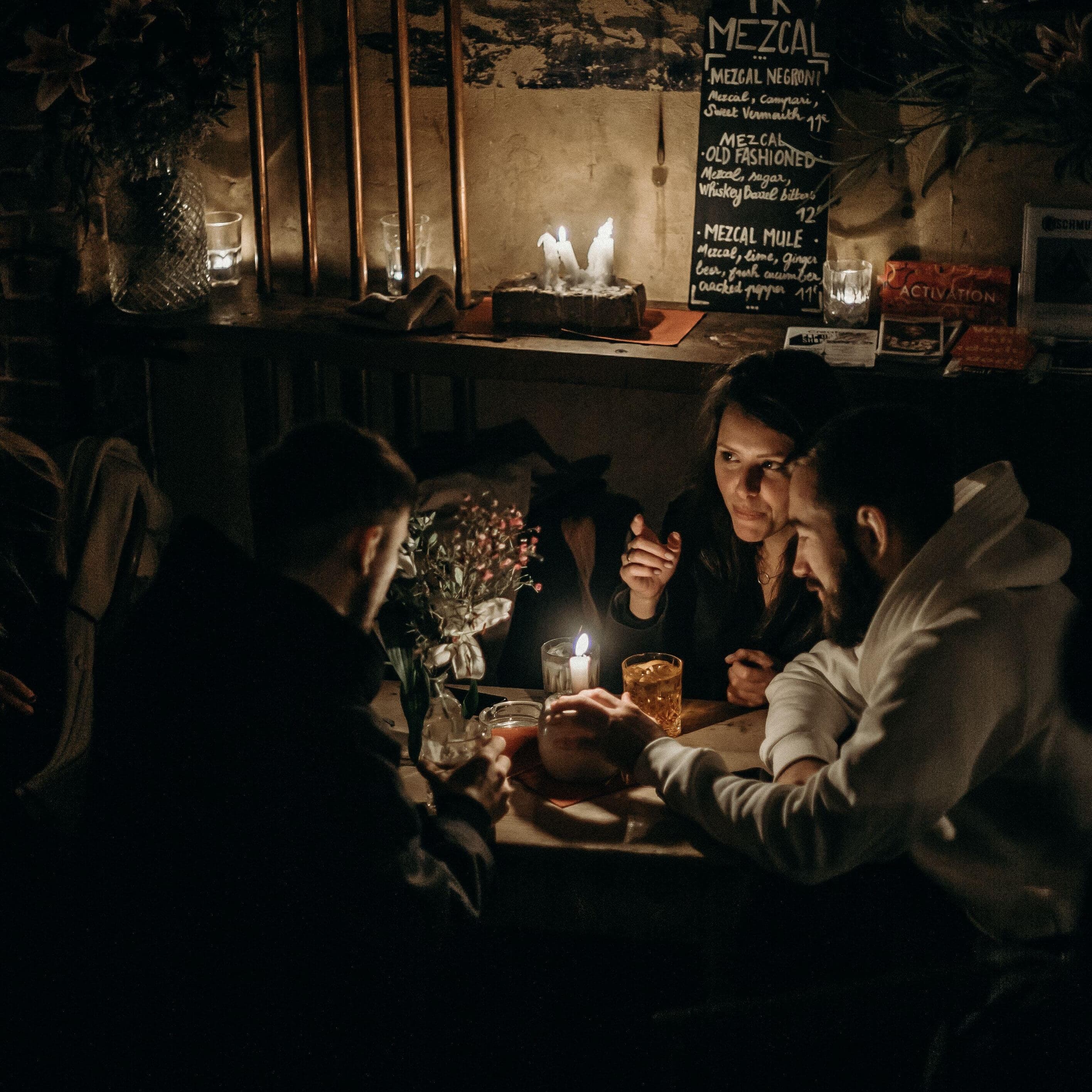 A candlelit table in a small bar, strangers deep in conversation