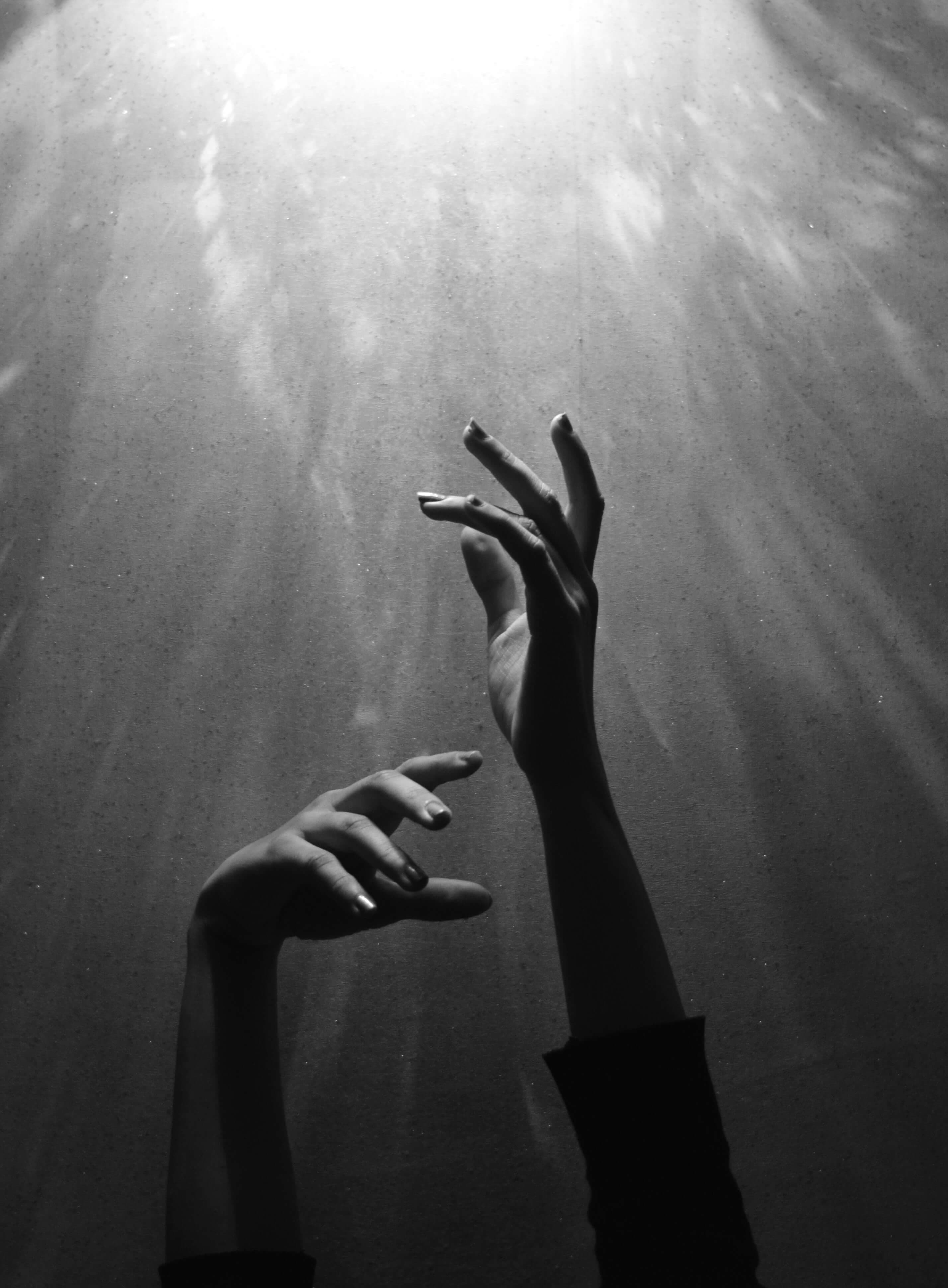 Hands reaching up through light